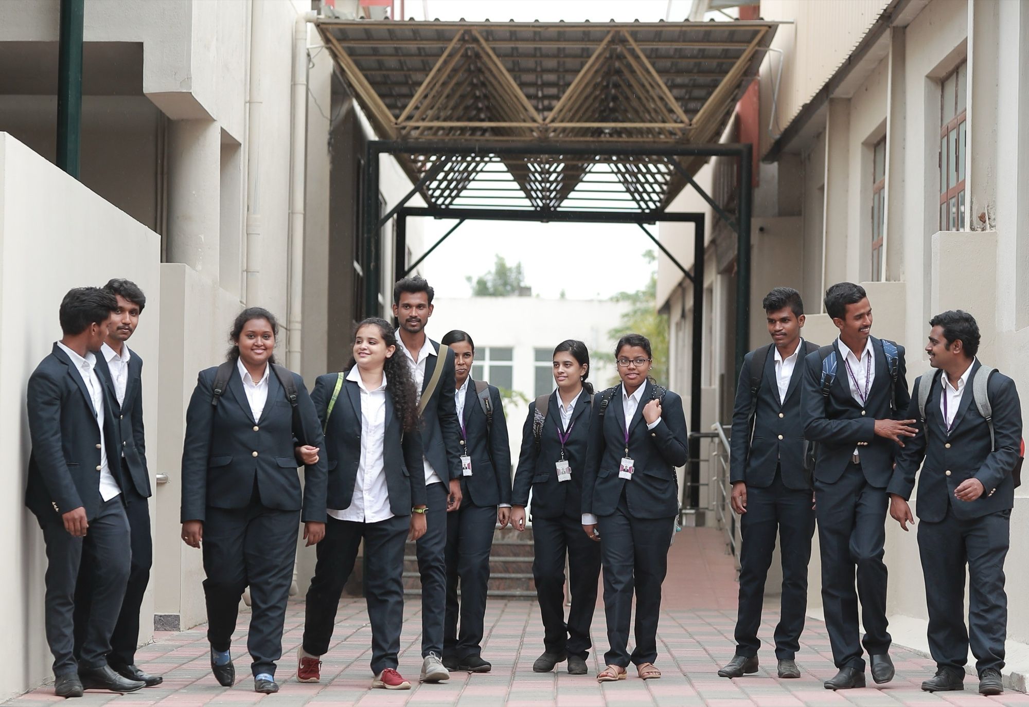 PMC Tech students in dark blazers walking along a covered walkway on the campus