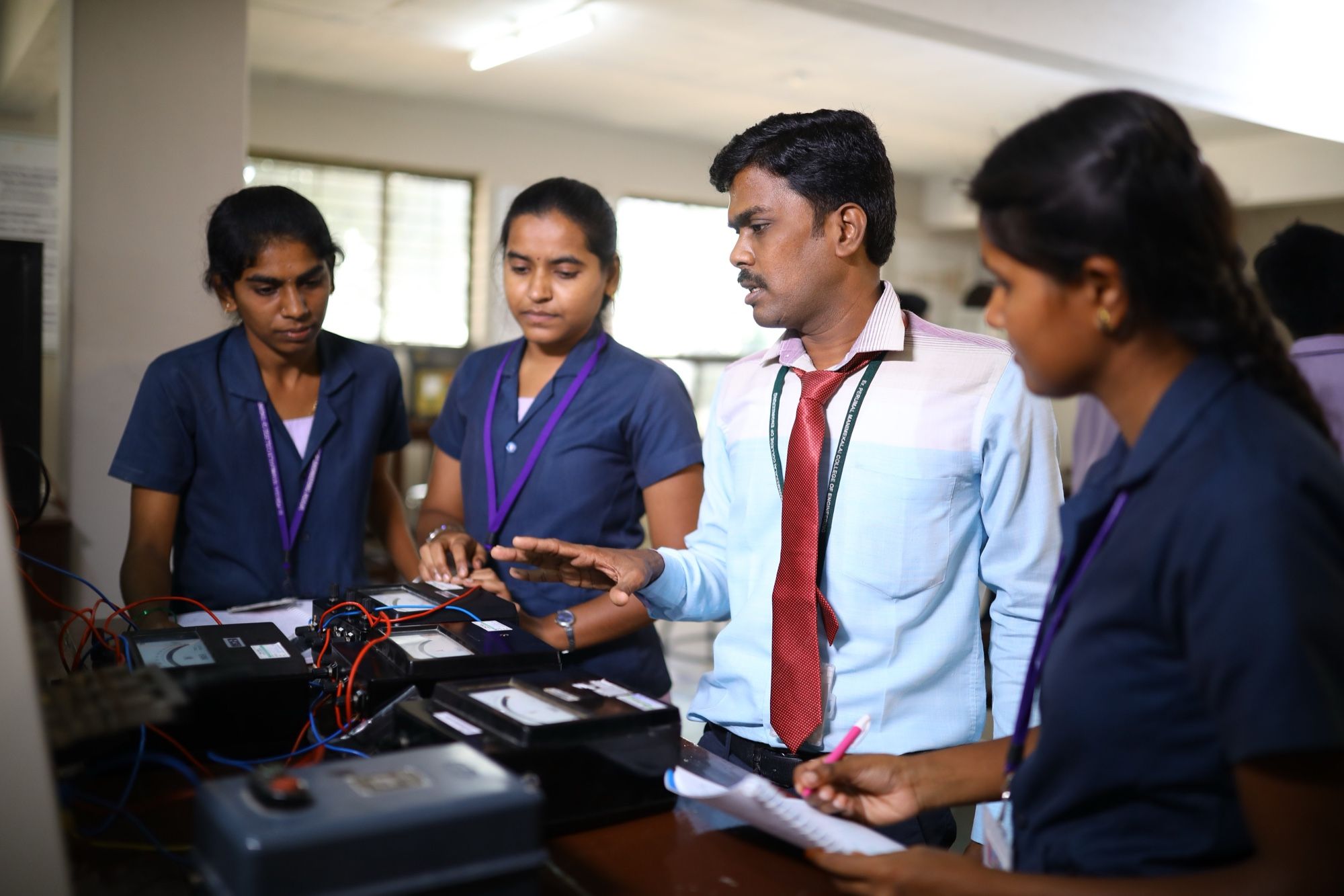 A PMC Tech faculty member explaining an electrical measurement set-up to students at a laboratory bench