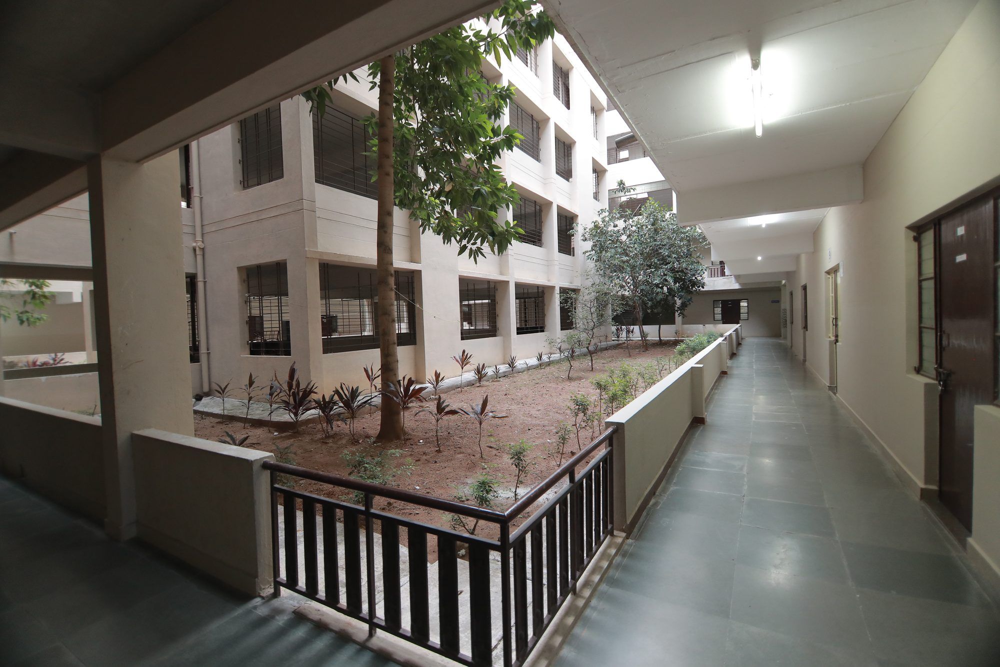 A PMC Tech hostel block around a planted courtyard, a corridor running along its ground floor