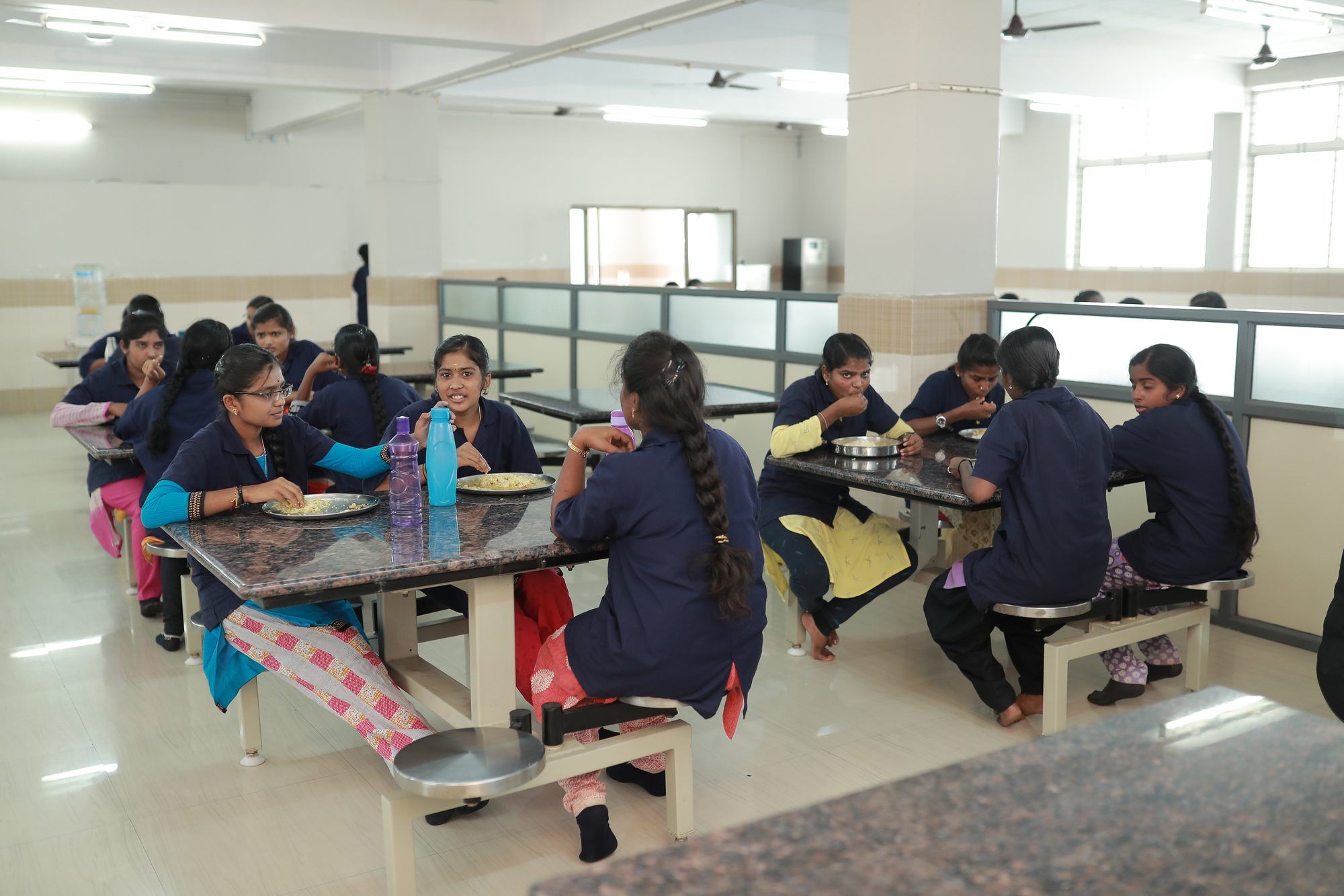 Students in uniform eating together at the tables of the hostel dining hall