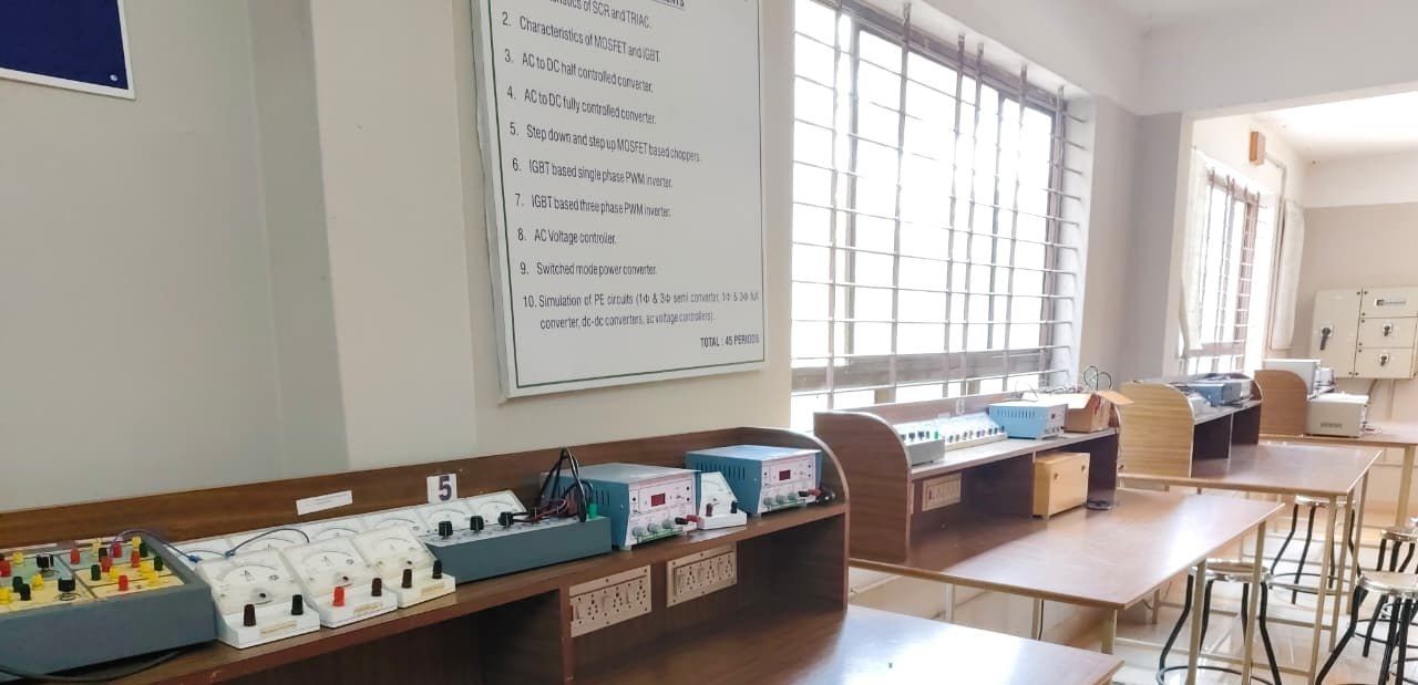 Rows of trainer kits on a wooden bench beneath a large notice listing experiments, with more benches and a barred window beyond.