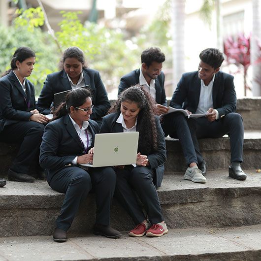 PMC Tech students in formal wear gathered on the campus steps around a laptop