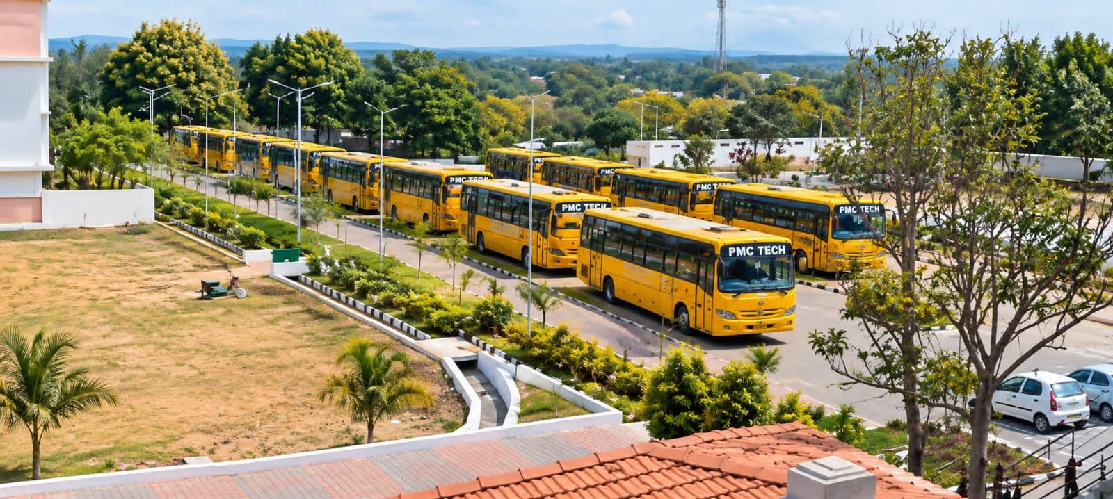 A row of yellow PMC Tech college buses parked along a tree-lined road on the campus